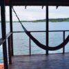 A hammock hanging from the side of a wooden deck.
