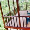 A wooden deck with railing and chairs on top of it.