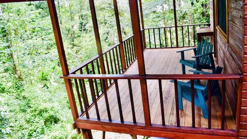 A wooden deck with railing and chairs on top of it.