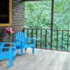 A porch with two blue chairs and a table.