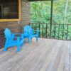 Two blue chairs on a porch with trees in the background.