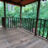A wooden deck with a railing and a view of trees.